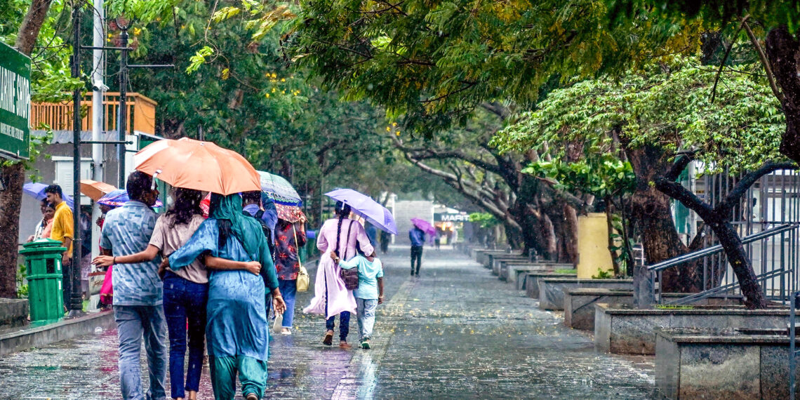 Kochi: Tourists walk under umbrellas during heavy rain at the Marine Drive walkway in Kochi on Thursday, May 29, 2025. (Photo: IANS)