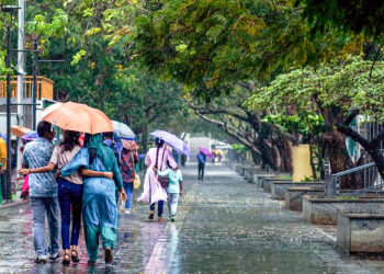 Kochi: Tourists walk under umbrellas during heavy rain at the Marine Drive walkway in Kochi on Thursday, May 29, 2025. (Photo: IANS)